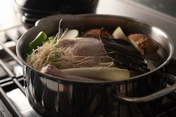 a whole chicken and vegetables are simmering in a stock pot