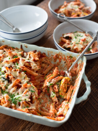 A big serving spoon is scooping up a portion to an individual serving bowl.