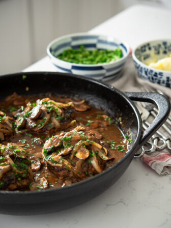 Salisbury Steak with Mushroom Onion Gravy is cooked in a cast iron skillet