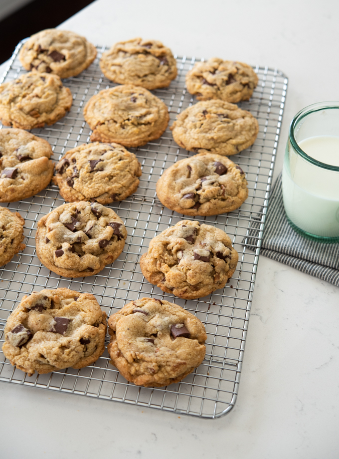 Crispy and chewy brown butter chocolate chip cookies are cooling on a wired rack.