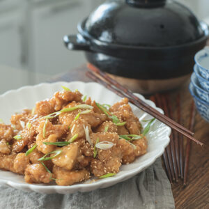 Crispy Chinese Lemon Chicken is garnished with green onion and chopsticks