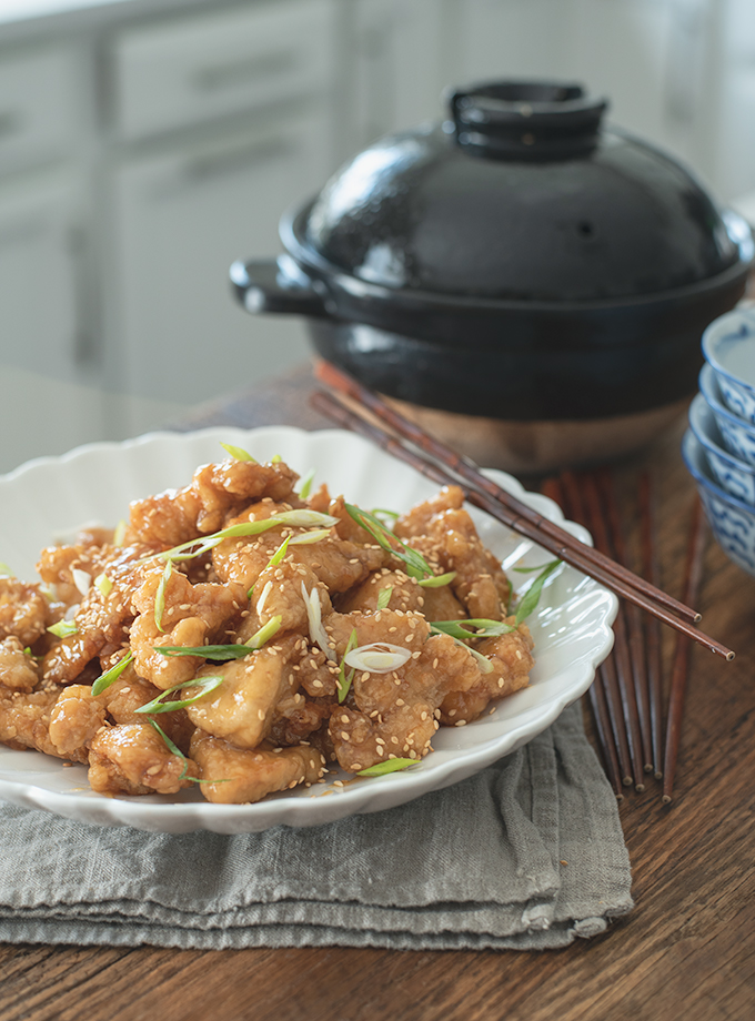 Crispy Chinese Lemon Chicken is garnished with green onion and chopsticks.