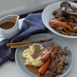 The Simplest Beef Pot Roast is served with mashed potato, Au Jus, and carrot.