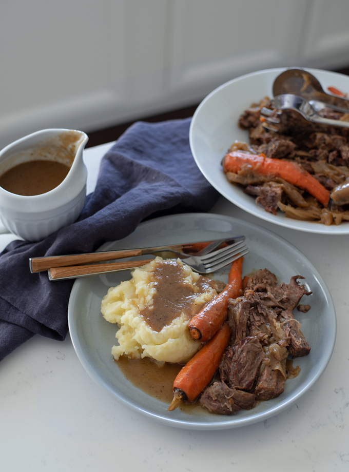 The Simplest Beef Pot Roast is served with mashed potato, Au Jus, and carrot.