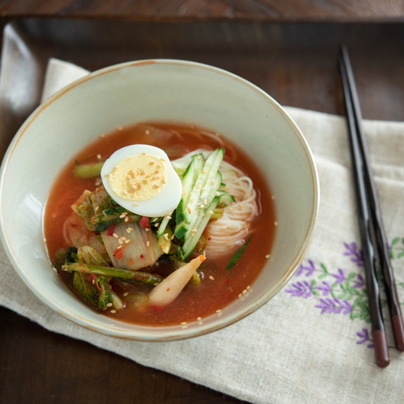 Yeolmu kimchi noodle soup topped with cucumber, boiled egg, and young radish kimchi