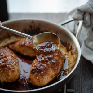 Sticky glaze made with apricot preserve is spooned over chicken breast.