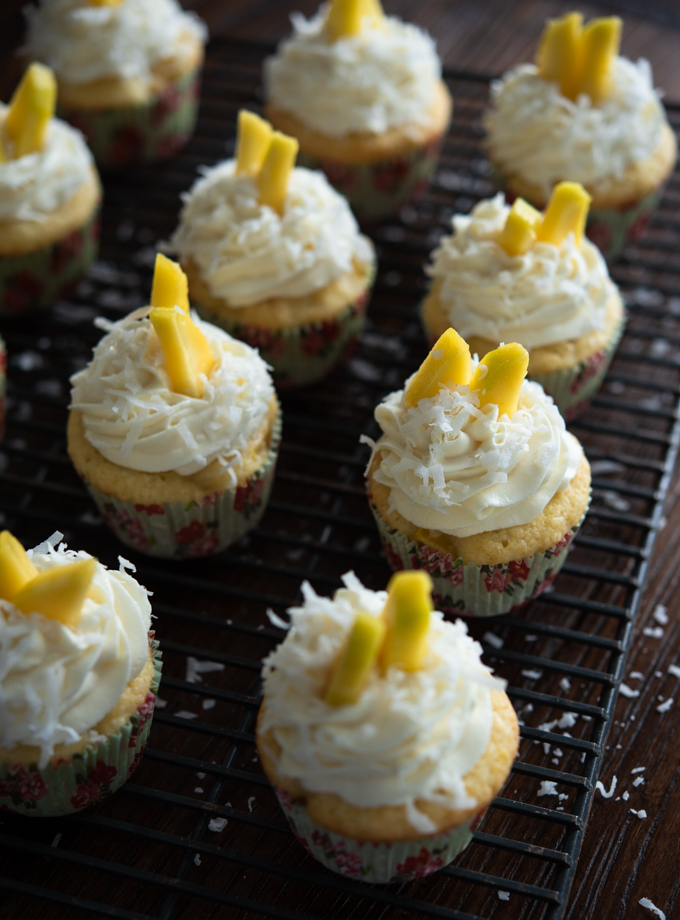 Mango Coconut Cupcakes are decorated with honey cream cheese frosting and fresh mango slices.