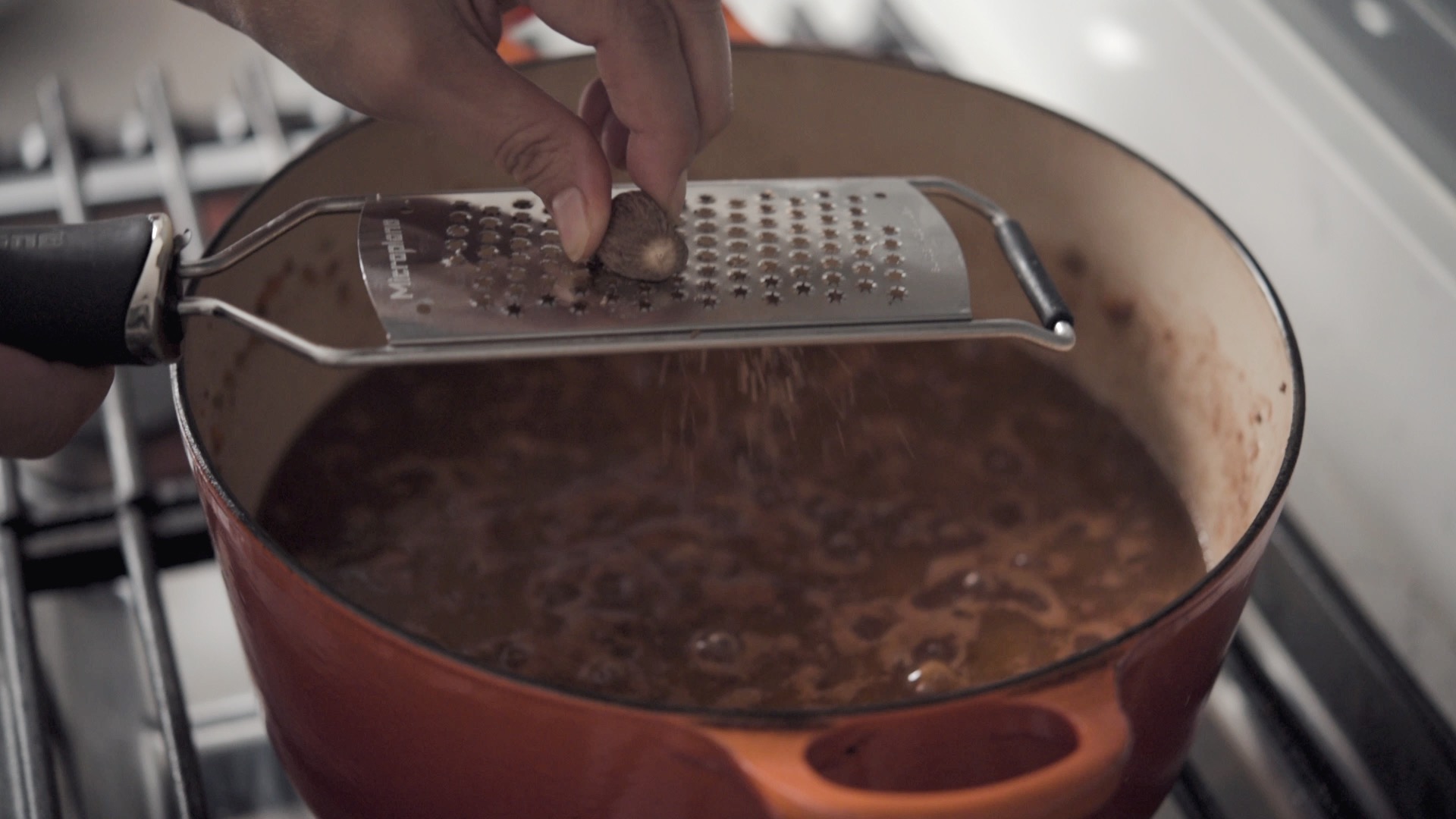 Nutmeg grating over the simmering pot of ragu bolognese.