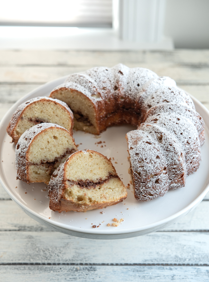 Slices of apple Cinnamon Bundt Cake with cinnamon walnut filling are on a cake stand