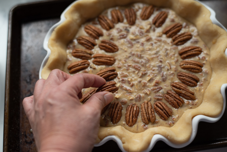 Whole pecan halves are arranged on top of pie filling for decoration.