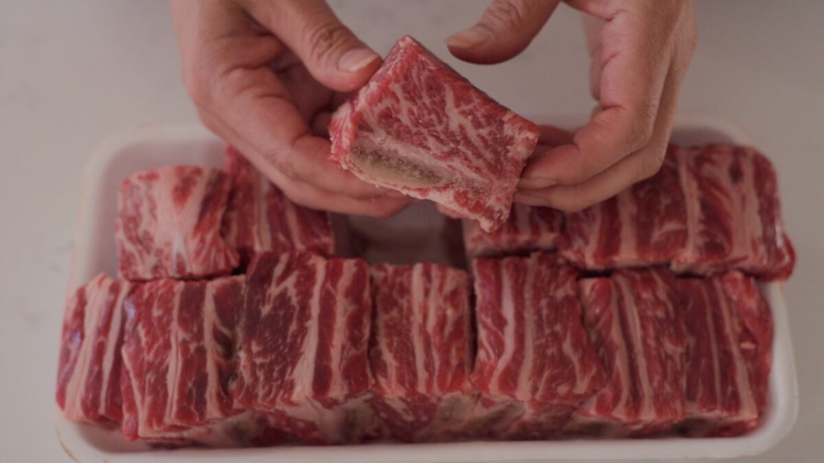Korean beef short ribs are showing the marbled look on the side with bone attached.