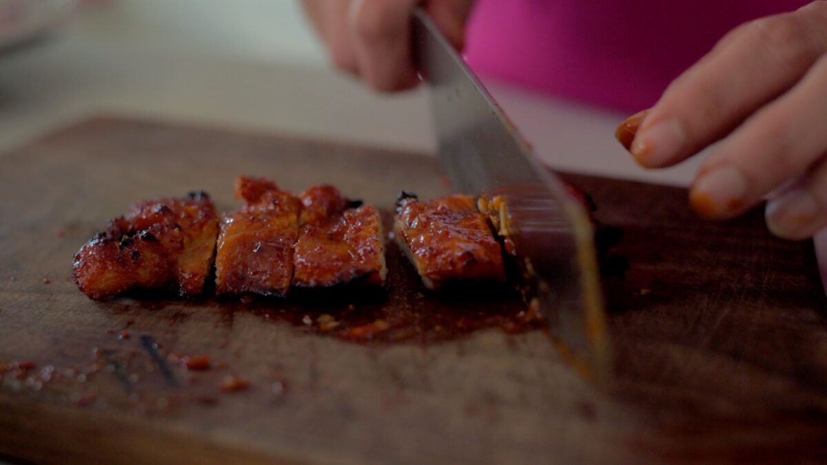 Broiled Korean chicken barbecue is sliced on a cutting board.