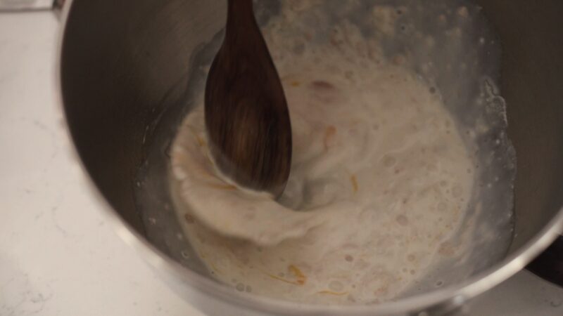 Wet ingredients mixed with a wooden spoon to make milk bread recipe.