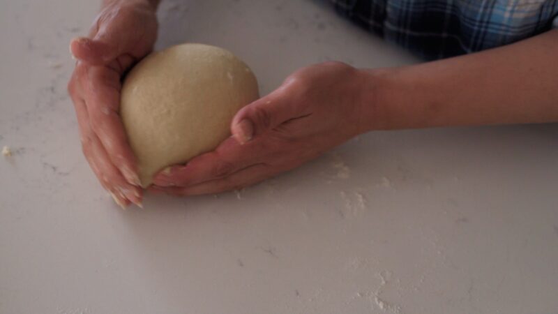 Easy milk bread dough handled by hands.