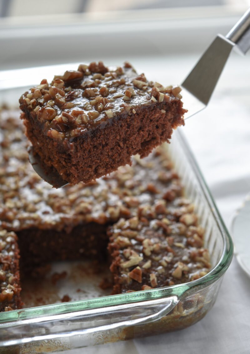 A slice of chocolate oatmeal cake topped with pecan caramel topping is served.