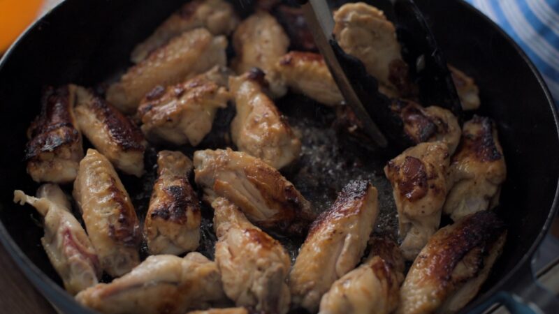 Chicken wings are browned in a pan.