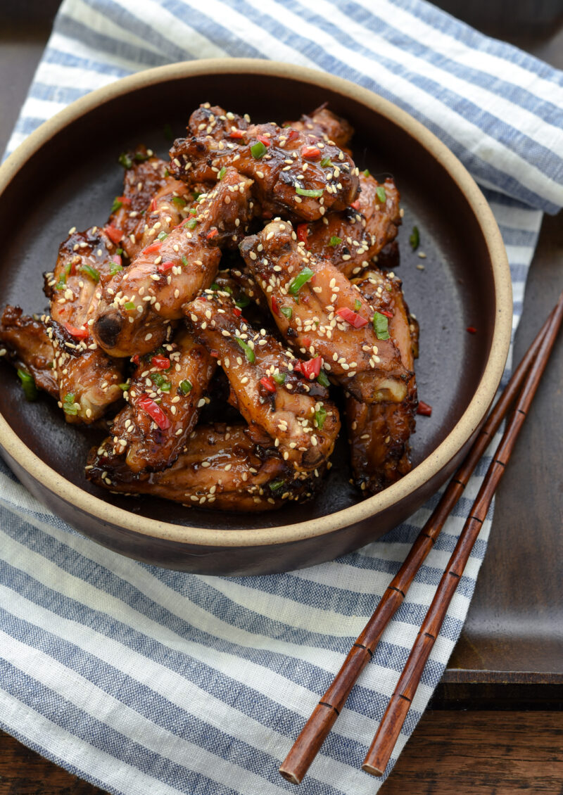 Korean honey garlic chicken coated with sticky sauce is plated and served on a white and blue napkin.