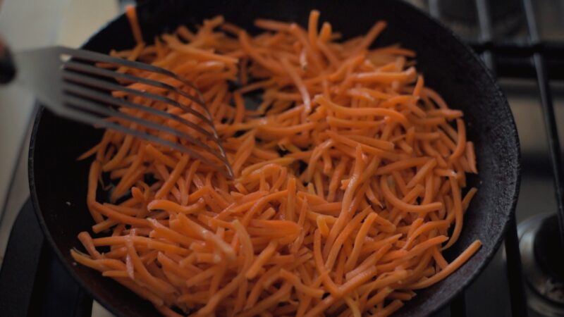 Shredded carrots are cooking in a skillet