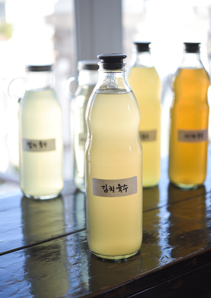 Stock for making kimchi is stored in a glass bottle with a Korean label attached.