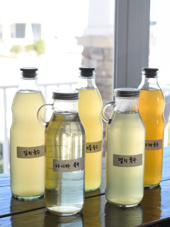 Bottles of various Korean soup stocks with their labels are placed on a counter.
