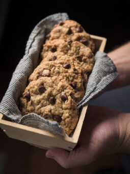 Chocolate wheat germ cookies are presented in a cloth lined container.