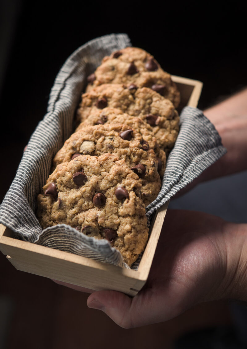 Chocolate wheat germ cookies are presented in a cloth lined container.