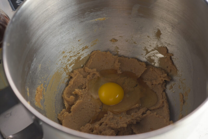 An egg is added to a creamed butter and brown sugar mixture.