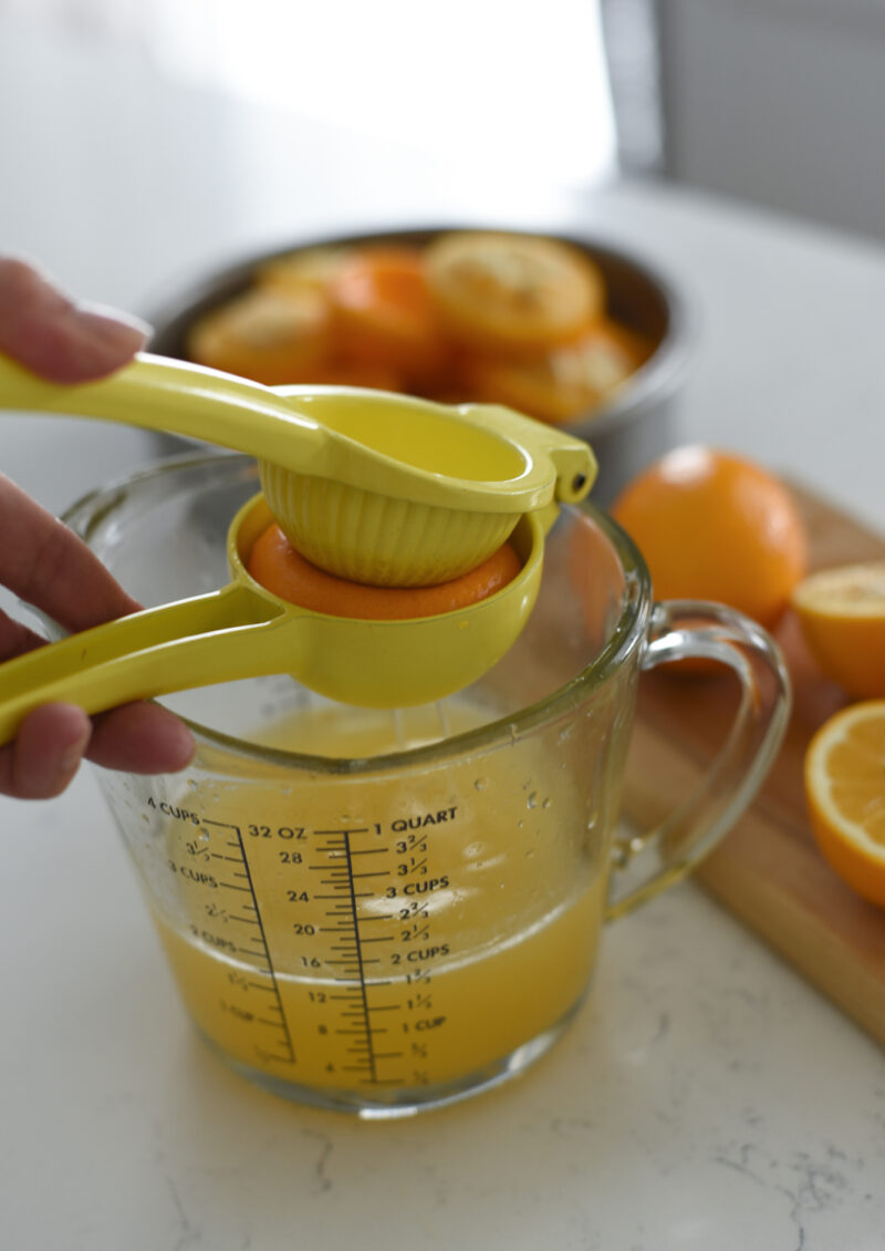A lemon juicer is squeezing out Meyer lemon into a glass container.