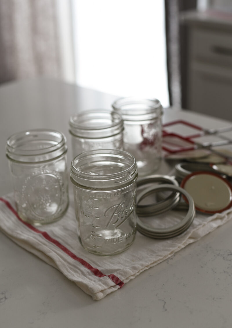 Sterilized jars are cooling and drying over a clean kitchen cloth.