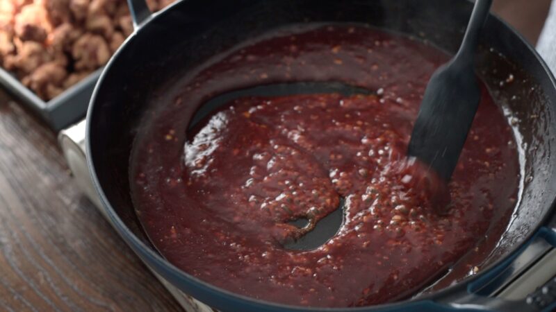 The sticky glaze for Korean chicken nuggets is boiling up in a pan.