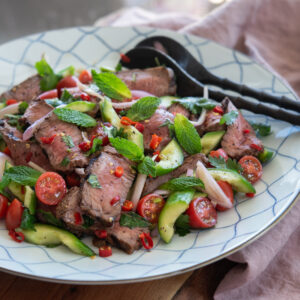 Thai beef salad is tossed with cucumber, tomato, shallot, and fresh red chili.