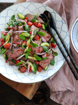 Thai beef salad (Yum Nua) is tossed with cucumber, tomato, shallot, and fresh red chili.