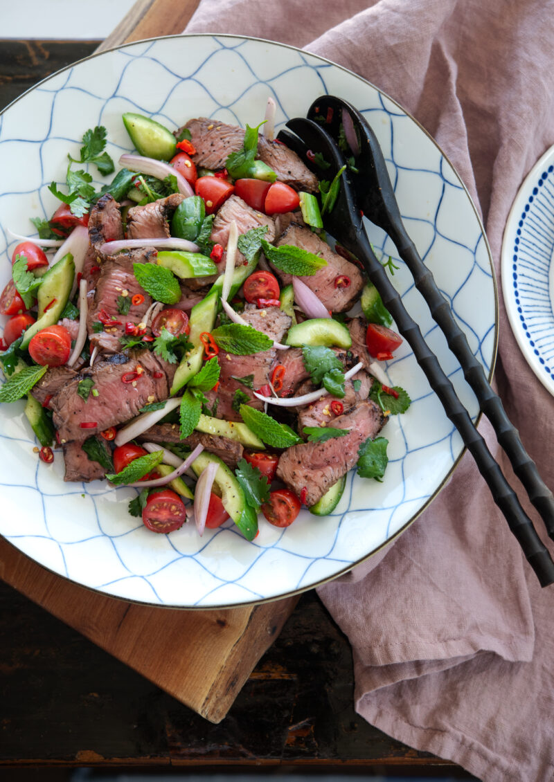 Thai beef salad is tossed with cucumber, tomato,  shallot, and fresh red chili.