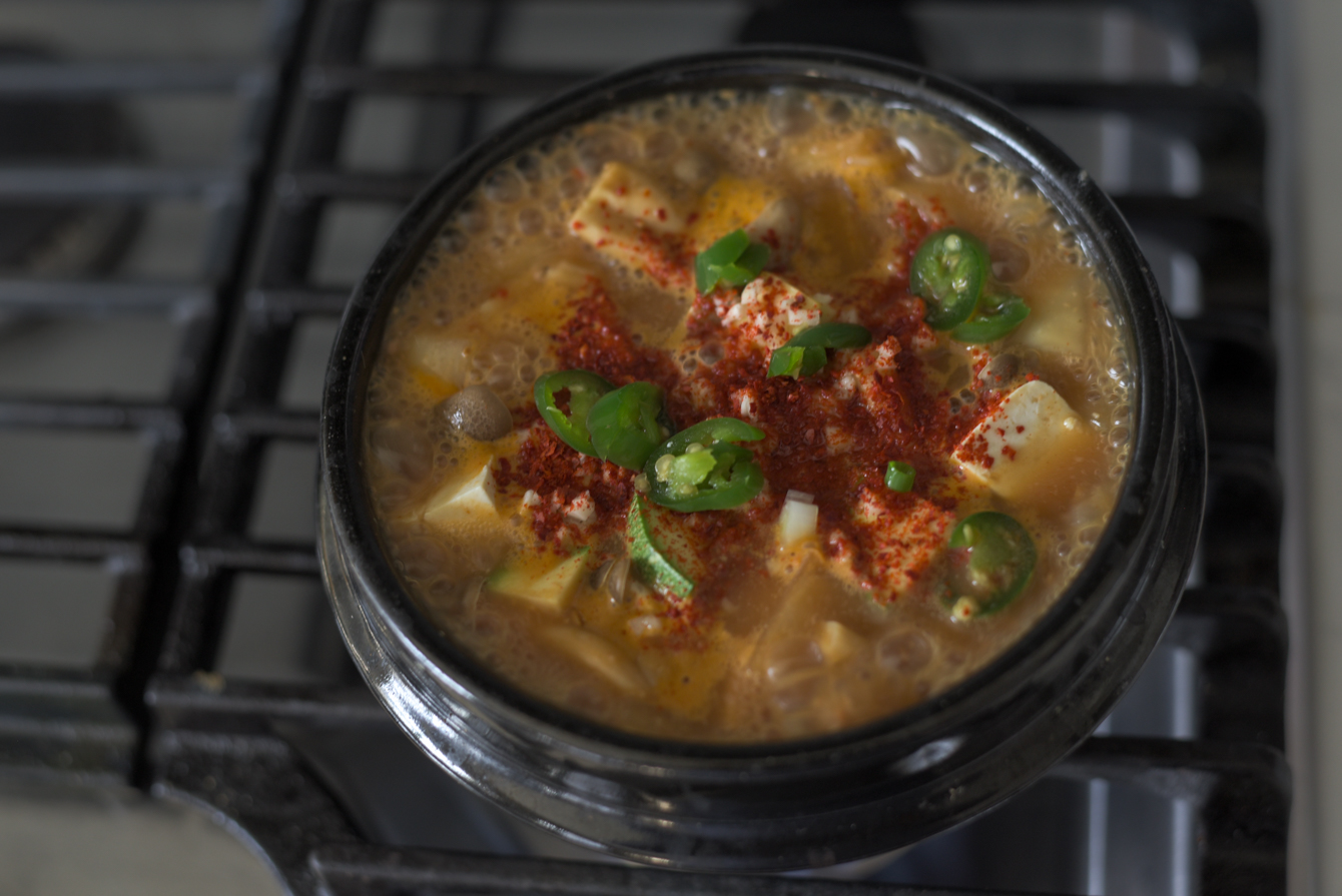 Gochugaru and green chilies added to boiling doenjang jjigae
