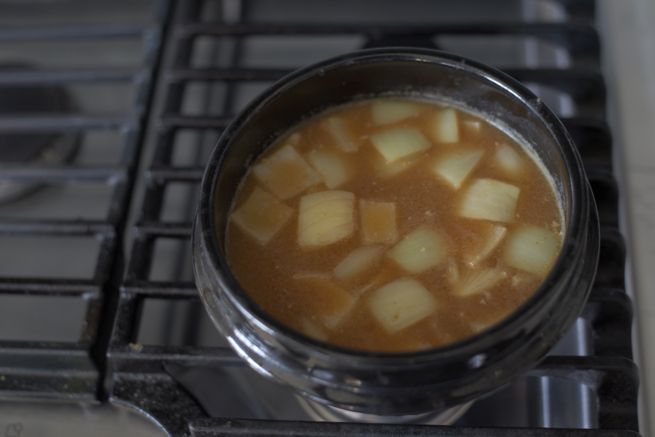 Diced onion added to simmering doenjang broth in a pot
