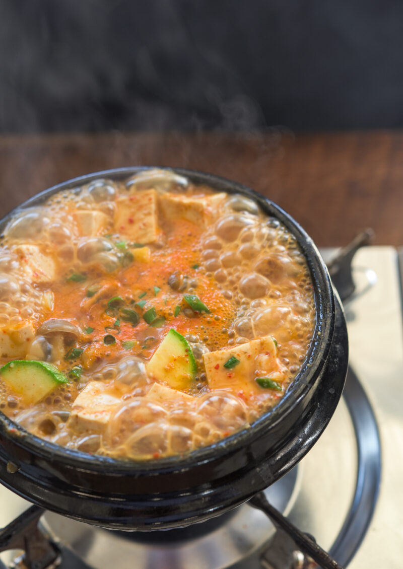 Korean soybean paste stew (doenjang jjigae) is boiling in a Korean stone pot.