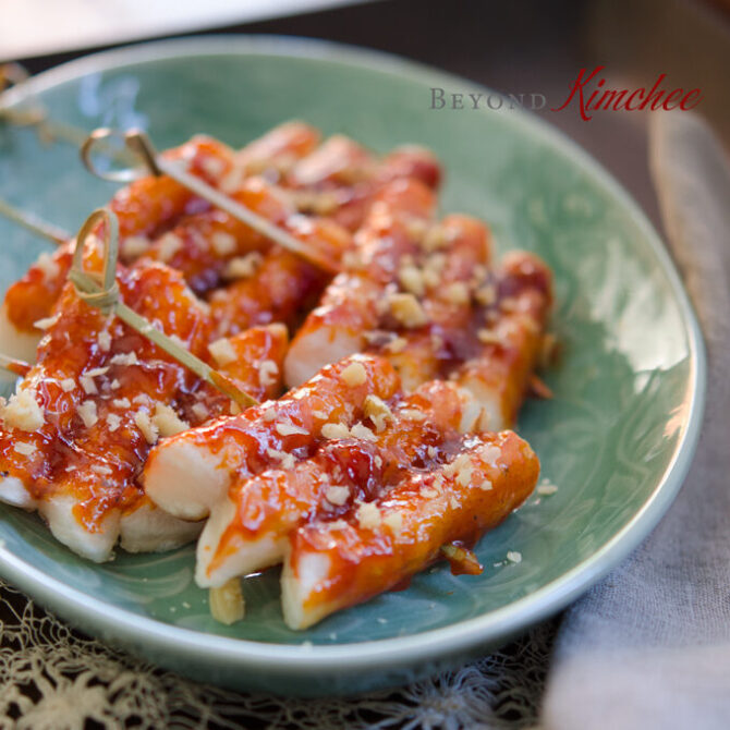 Rice Cakes are on skewers and glazed with sauce made with Korean chili paste (gochujang).