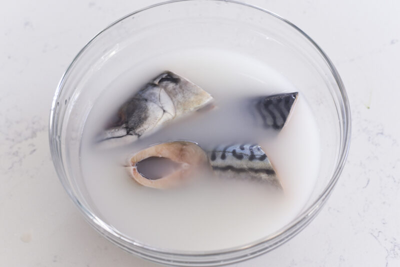Mackerel slices are soaking in rice water in a bowl.