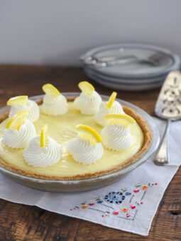 No bake sour cream lemon pie is made with graham cookie crust and garnished with whipped cream.