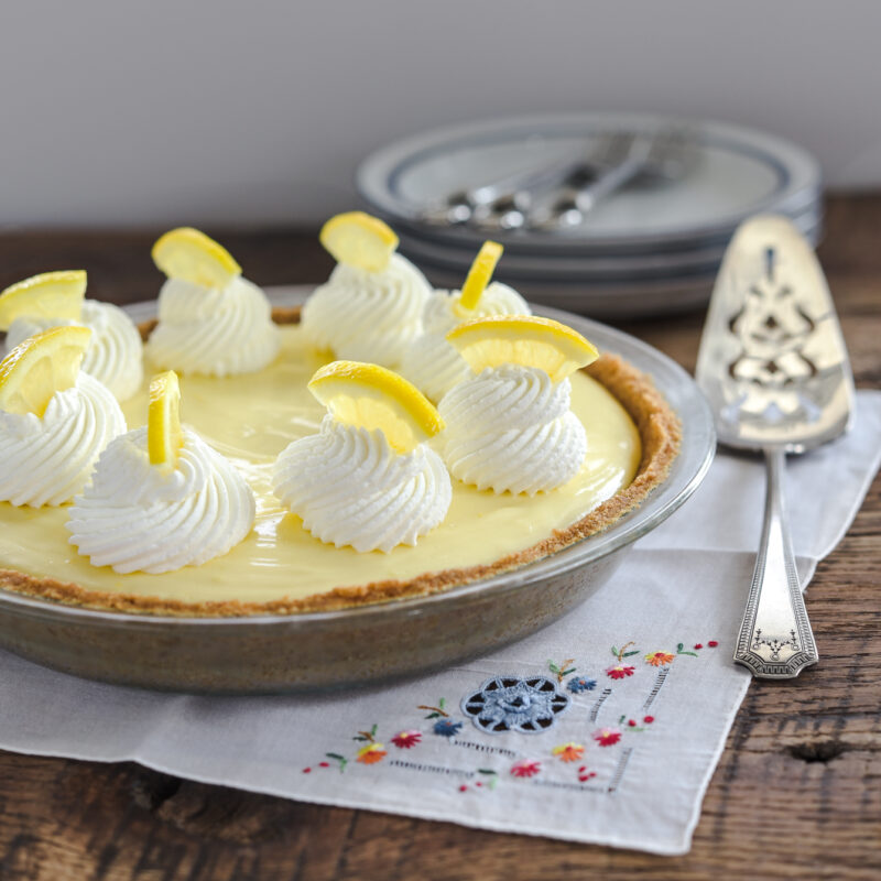 This no bake sour cream lemon pie with graham cookie crust is decorated with whipped cream and lemon slices on top