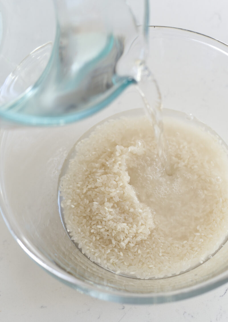 Water is poured on a bowl of uncooked rice.