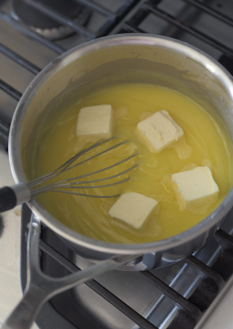 4 pieces of butter is added to lemon custard in a pan.