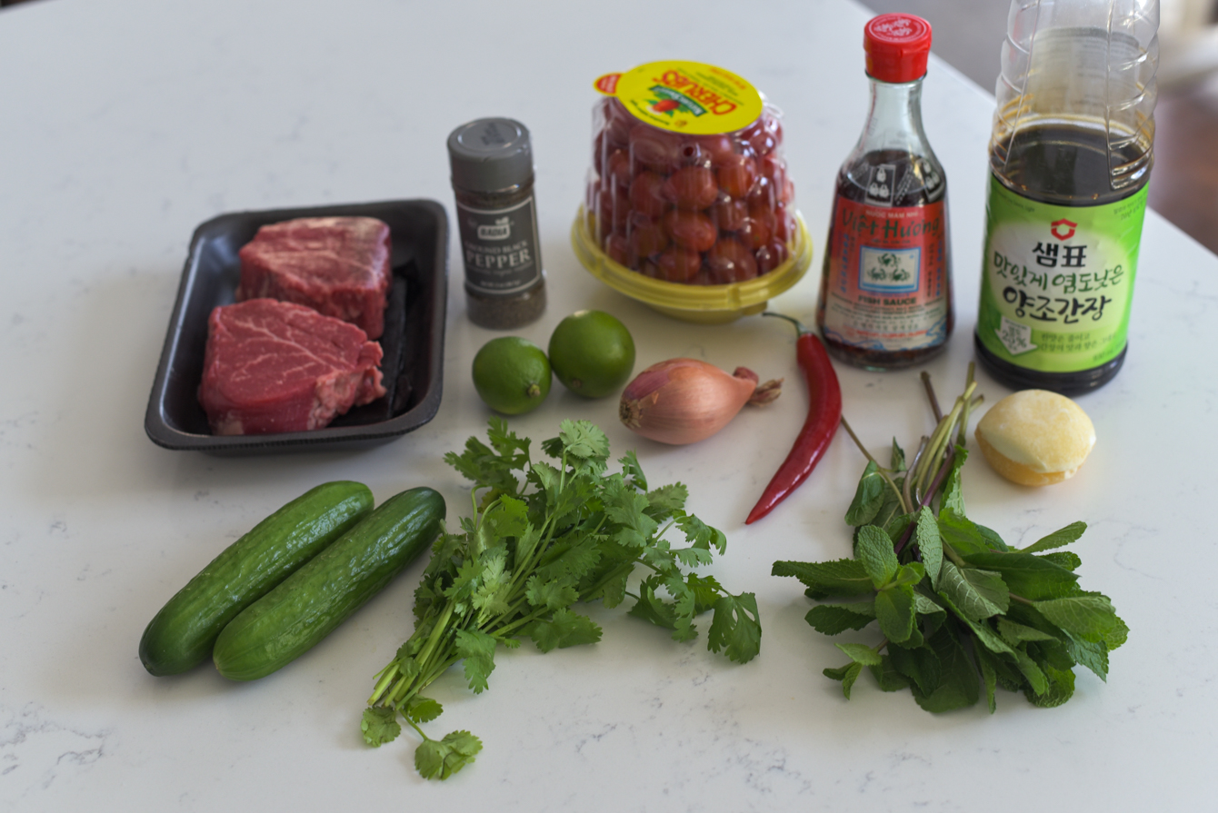 Thai beef salad ingredients are laid on a counter.