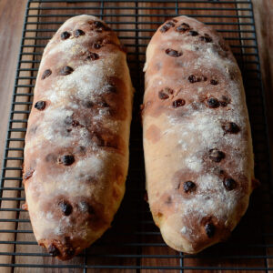 Two loaves of club med white chocolate bread are cooling on a wired rack.