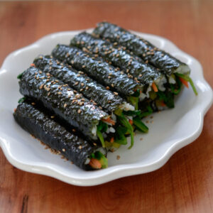 Mini Seaweed Rice Rolls (mayak gimbap/kimbap) are garnished with toasted sesame seeds.