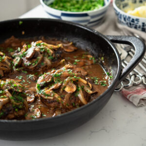Salisbury Steak with Mushroom Onion Gravy is cooked in a cast iron skillet.