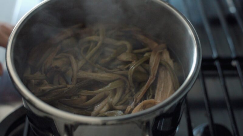 Dried taro stem is simmering in a pot of hot water to rehydrate.