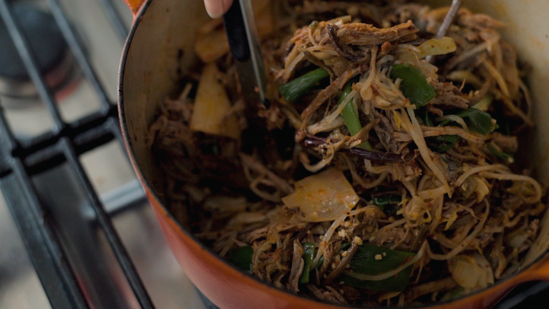 Shredded beef and vegetables coated with chili oil in a pot