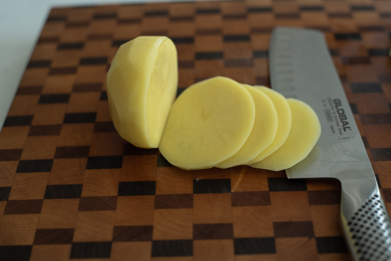 A peeled potato thinly sliced for making gamja bokkeum