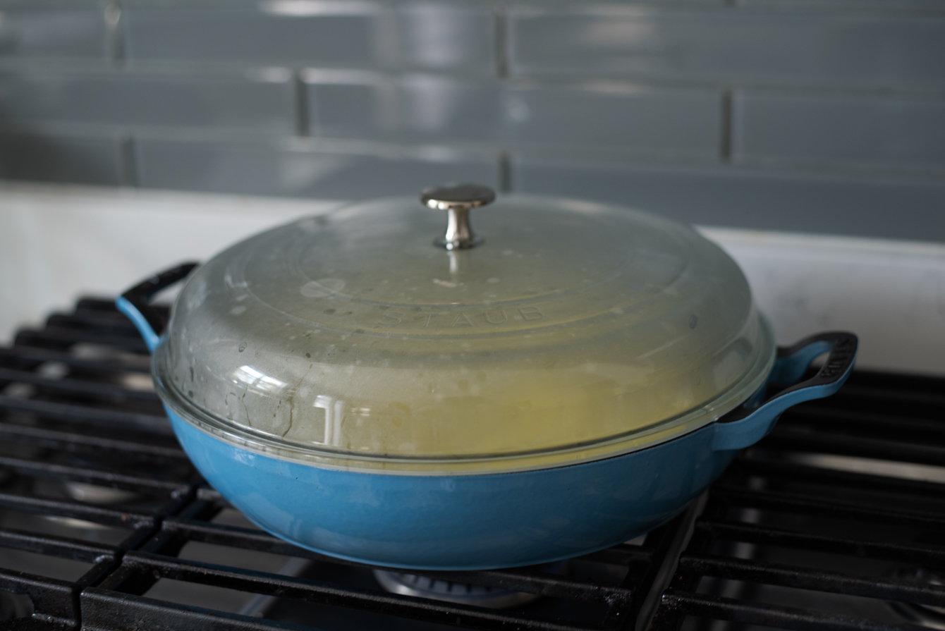 A glass lid covering the pan with potatoes